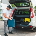 Person loads luggage into the trunk of an SUV. 
